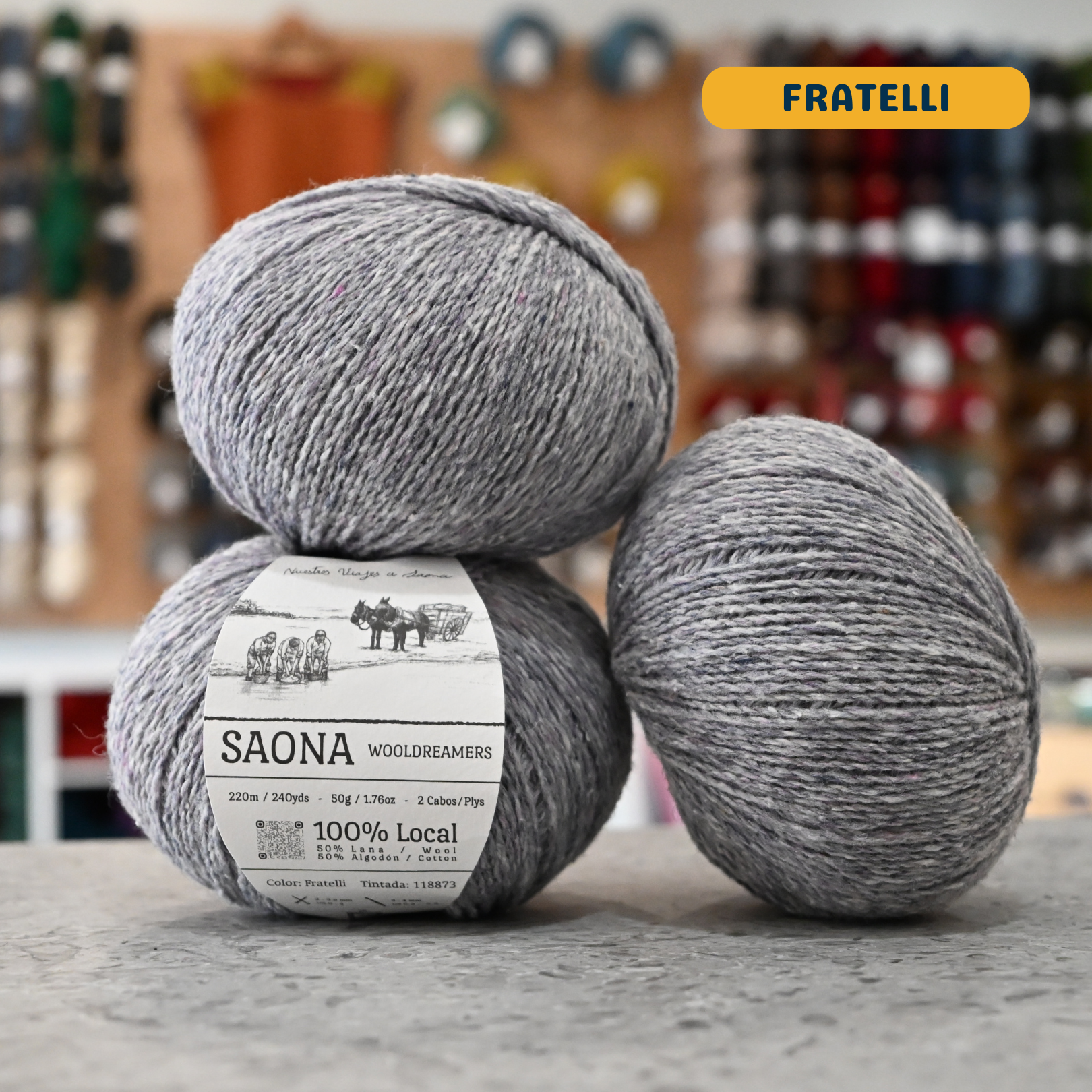 50g light blue-grey (fratelli) wool & cotton fingering yarn, 'Saona Wooldreamers' label visible, craft shop background (blurred)

