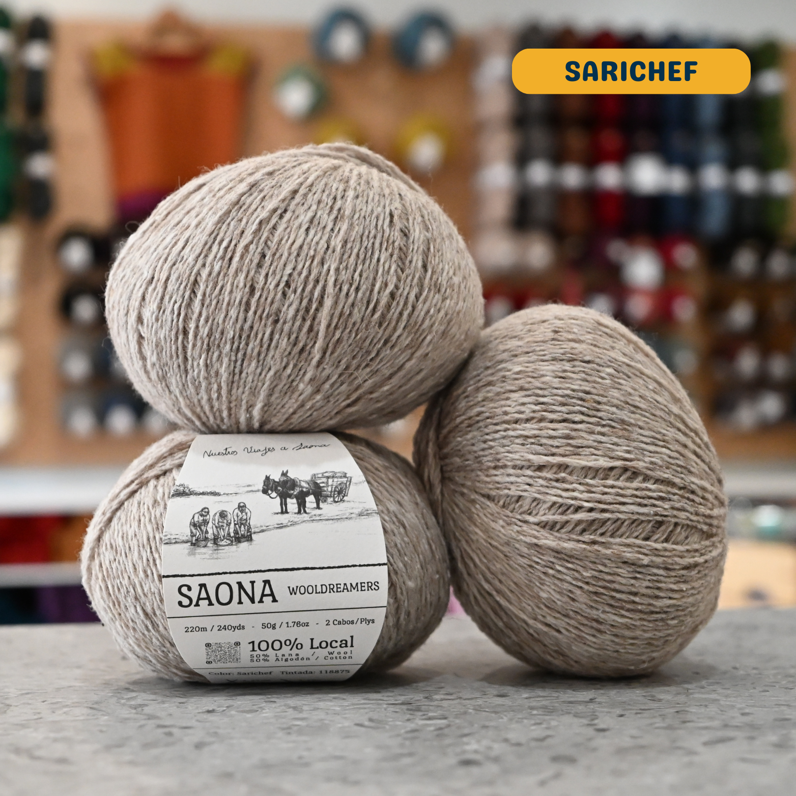 50g beige (sarichef) wool & cotton fingering yarn, 'Saona Wooldreamers' label visible, craft shop background (blurred)
