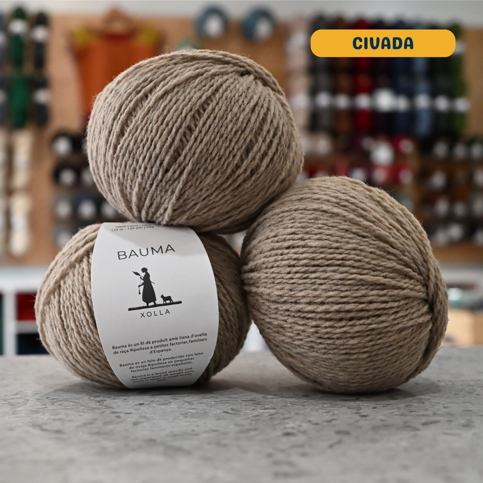 50g beige (civada) Spanish wool DK yarn, 'Bauma Xolla' label visible, craft shop background (blurred)