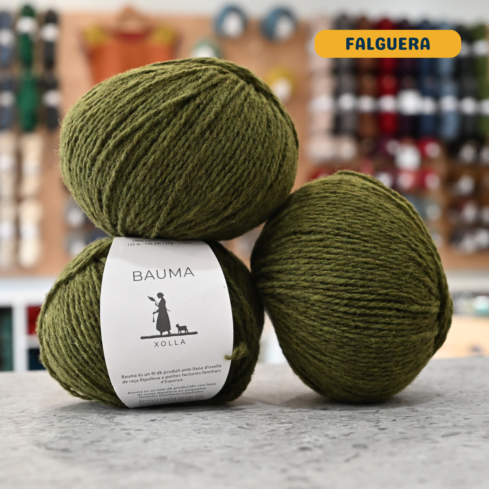 50g green (falguera) Spanish wool DK yarn, 'Bauma Xolla' label visible, craft shop background (blurred)
