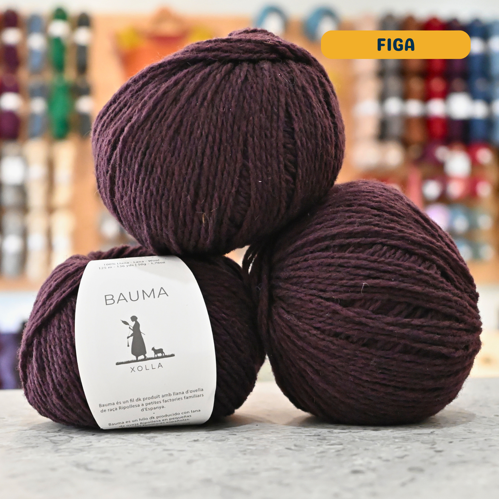 50g sark purple (figa) Spanish wool DK yarn, 'Bauma Xolla' label visible, craft shop background (blurred)