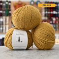 50g yellow (pol-len) Spanish wool DK yarn, 'Bauma Xolla' label visible, craft shop background (blurred)